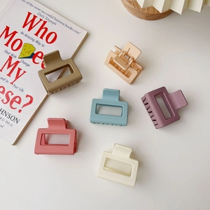 Set of six matte candy-colored square hair claws in assorted pastel shades on a white desk