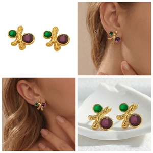 Détail macro de boucles d'oreilles géométriques en or martelé avec pierres émeraude et rubis