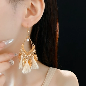 Close-up of bohemian leaf tassel earrings on model with golden finish and cream fringe