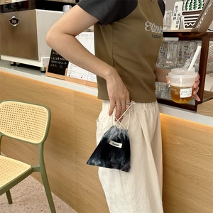 Detail of tie-dye corduroy drawstring bag with logo label in a cafe setting