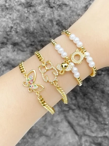 Detail of four gold bracelets set featuring butterfly, owl, elephant and pearl charms