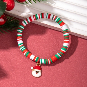 Detail of Christmas beaded bracelet with Santa Claus charm on festive red background
