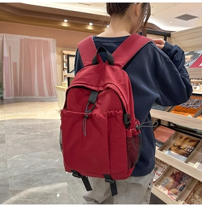 Rückansicht einer Studentin mit großem rotem Nylon-Rucksack in einer Bibliotheksumgebung