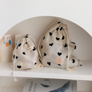 Champagne heart drawstring storage bag set in a minimalist white arched shelf display