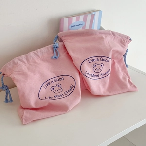 Detail of two pink drawstring pouches with cute bear prints and cotton linen texture