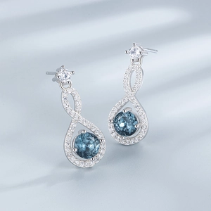 Eleganti orecchini a infinito in argento S925 con zaffiri blu su sfondo di seta