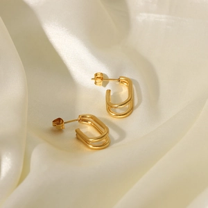 Detail of 18k gold plated double layered U-shaped hoop earrings on white silk