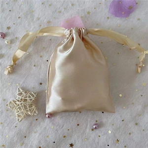 Macro detail of champagne satin drawstring pouch with ribbon on decorative mesh