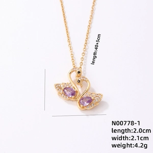 Elegant gold twin swan pendant necklace with purple and clear zircon stones on a chain