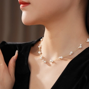 Détail d'un élégant collier double rang avec perles et chaîne dorée sur un mannequin