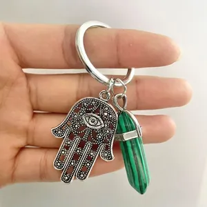 Macro detail of silver Hamsa Hand keychain with green malachite hexagonal crystal pillar