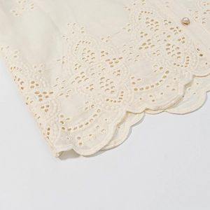 Detail of lace embroidery edge and pearl button on French style cream blouse fabric