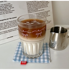 Detail of pink bow ribbon glass cup with textured base holding layered iced latte
