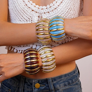 Detail of chunky acrylic ribbed bracelets in gold finish with marbled resin textures
