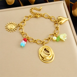 Detail of a golden charm bracelet featuring sun, heart, floral motifs and colored beads