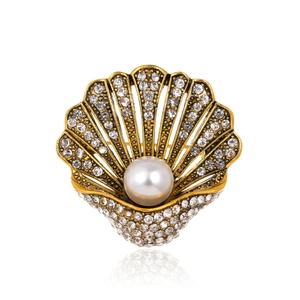 Vintage gold shell brooch with crystal rhinestones and centered white pearl on white background