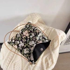 Close-up of a floral pattern crossbody bag with magnetic closure and slim shoulder strap