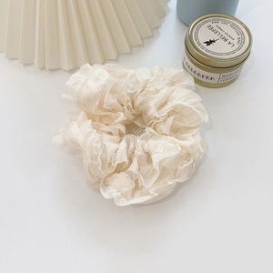 Elegant beige ruffled scrunchie made of airy fabric shown on a minimalist background