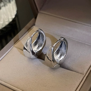 Close-up of silver bean earrings with mirror finish in a velvet beige jewelry box