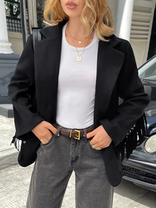 Detail of elegant black jacket featuring decorative fringe and luxury gold accessories