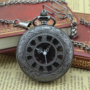 Vintage black roman numeral pocket watch with embossed pattern on a retro book