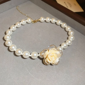 Macro detail of multilayer pearl necklace with diamond-encrusted rose flower pendant