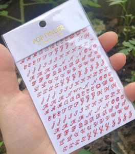 Detailed view of red handwritten 3D English letter nail stickers model WG720 held by hand