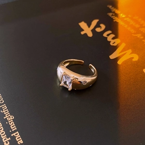 Macro detail of vintage gold open ring with square zircon stone on Monet art book