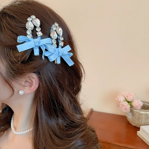Détails des barrettes nœuds bleu clair avec strass portées sur cheveux ondulés