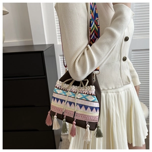 Detailed close-up of colorful ethnic embroidery and tassels on a brown bucket bag