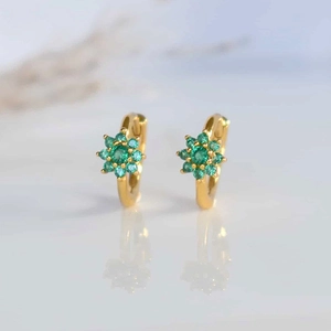 Macro shot of gold-plated hoop earrings with green zircon flower cluster design