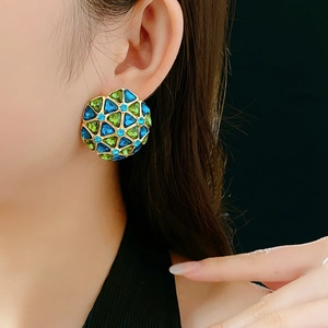 Detail of vintage geometric earrings with green and blue crystals on gold base