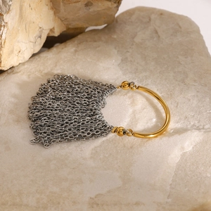Two-tone stainless steel ring with gold band and silver chain tassel on natural stone