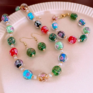 Detail view of handmade glass bead jewelry set with colorful patterns and gold accents