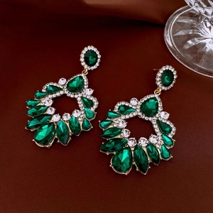 Detailed macro view of vintage emerald green waterdrop earrings with crystal pavé on velvet