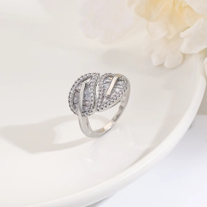 Close-up of silver leaf ring with pavé zircons on white ceramic plate with flowers