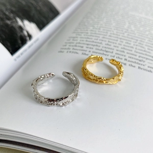 Detail of gold and silver open rings with irregular molten texture on open book pages