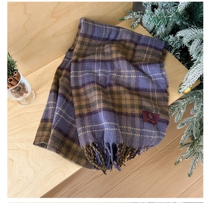 Detailed view of soft purple and brown plaid scarf with fringe on rustic wooden surface