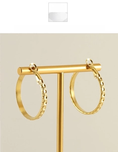 Détail de boucles d'oreilles créoles dorées avec texture nid d'abeille sur support