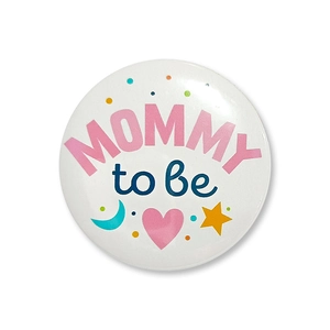 Close-up of a white Mommy to be badge with blue and pink fonts for baby shower parties