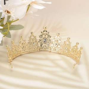 Close-up of golden hollow crown with rhinestones under soft palm leaf shadows