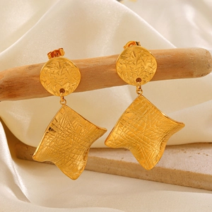Golden irregular square earrings with brushed metal texture on white silk background