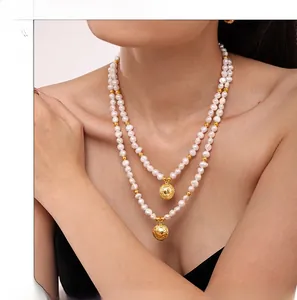 Detail showing layered white freshwater pearl necklace with engraved gold hollow pendants