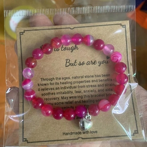 Pink zebra stone bead bracelet with silver heart charm on card in packaging