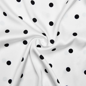 Dettaglio del tessuto in raso bianco a pois neri che mostra texture liscia e caduta