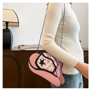 Pink cowboy hat shaped crossbody bag with star detail and metal chain strap shown on model