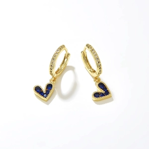 Detail of gold heart earrings with blue zircons and white crystals on polished metal