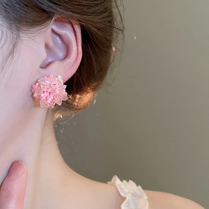 Nahaufnahme eines rosa Perlenblumen-Ohrsteckers aus gewebten Kristallen am Modelohr
