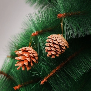Golden glitter pine cone ornament hanging on a lush green Christmas tree branch