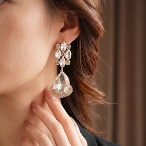 Vintage gold-plated teardrop earrings with crystals, shown worn by a model